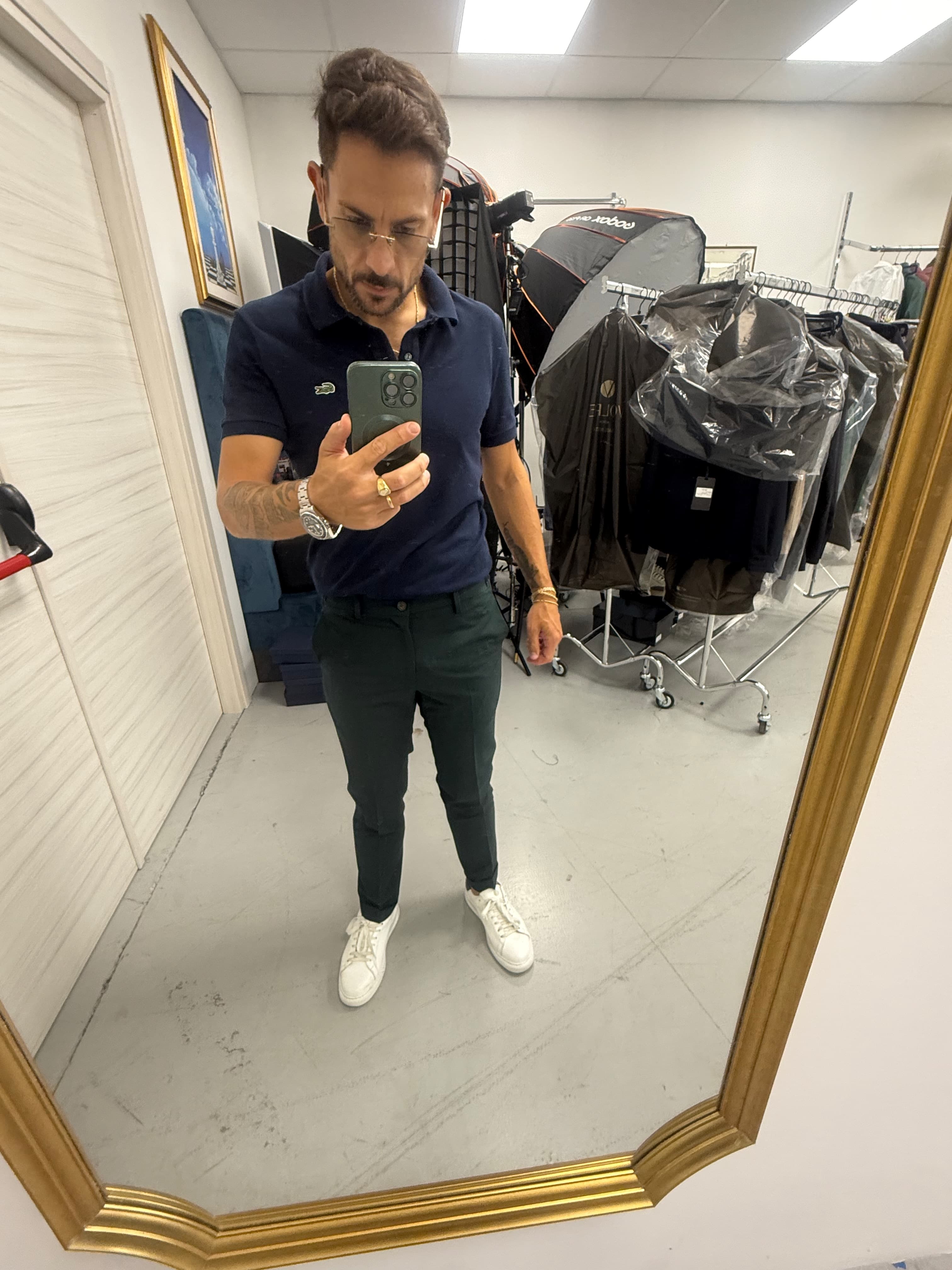 Angelo Maria Volpe in polo blu, tra capi d’abbigliamento e attrezzatura fotografica